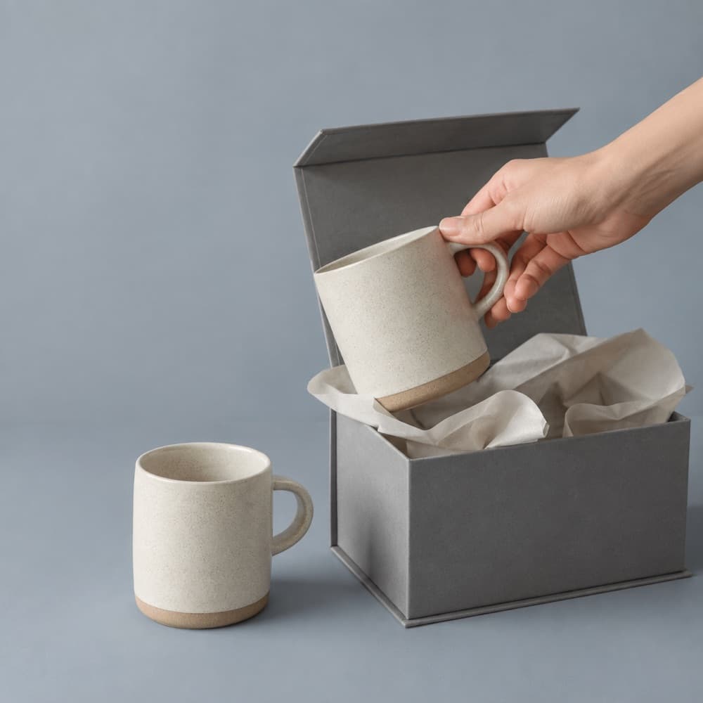 A hand holding the Gift Pair Set — Two Cups in a Box, showing the scale of the cup against a hand