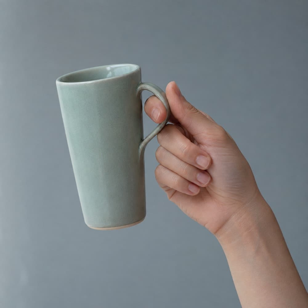 A hand holding the Slim Mug 280 ml, showing the scale of the cup against a hand