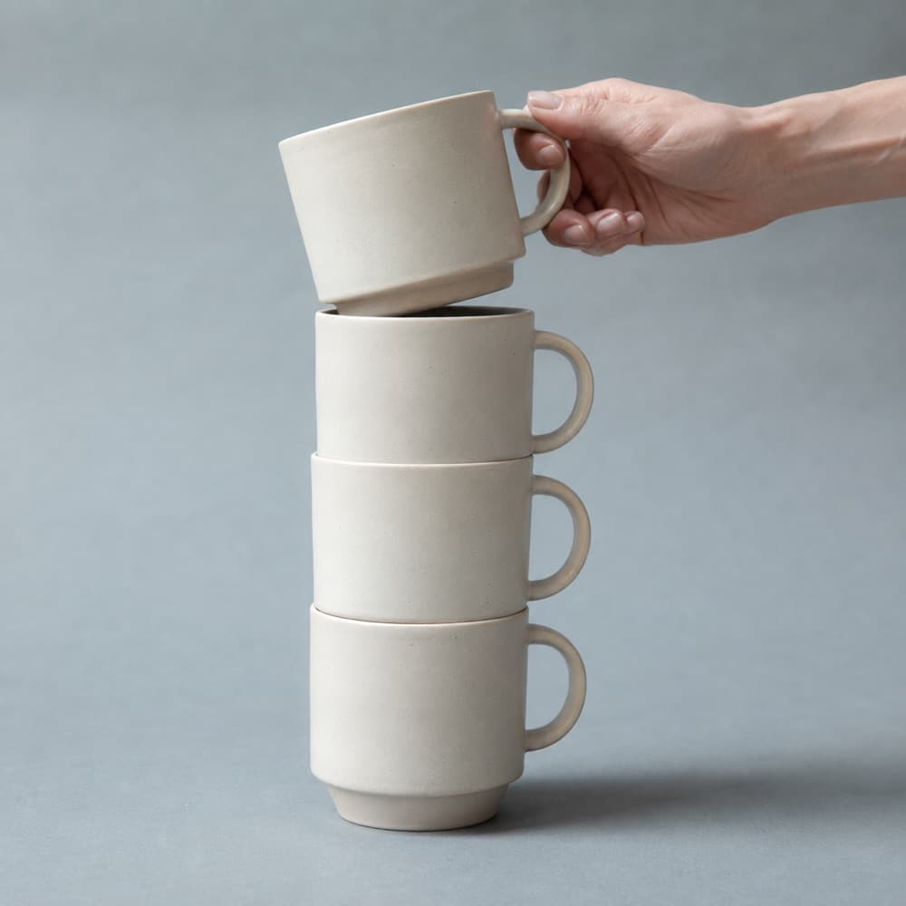 A hand holding the Stacking Mug 300 ml, showing the scale of the cup against a hand
