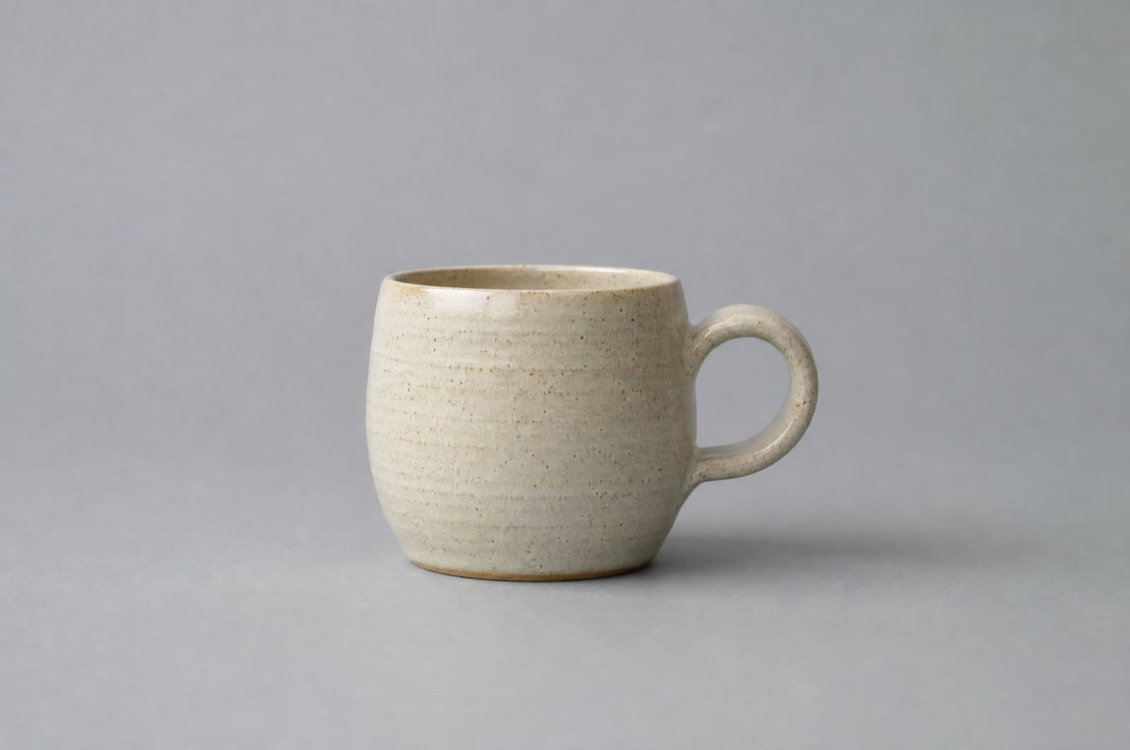 An Everyday Mug 300 ml in cream speckled stoneware, photographed straight on with the handle to the right
